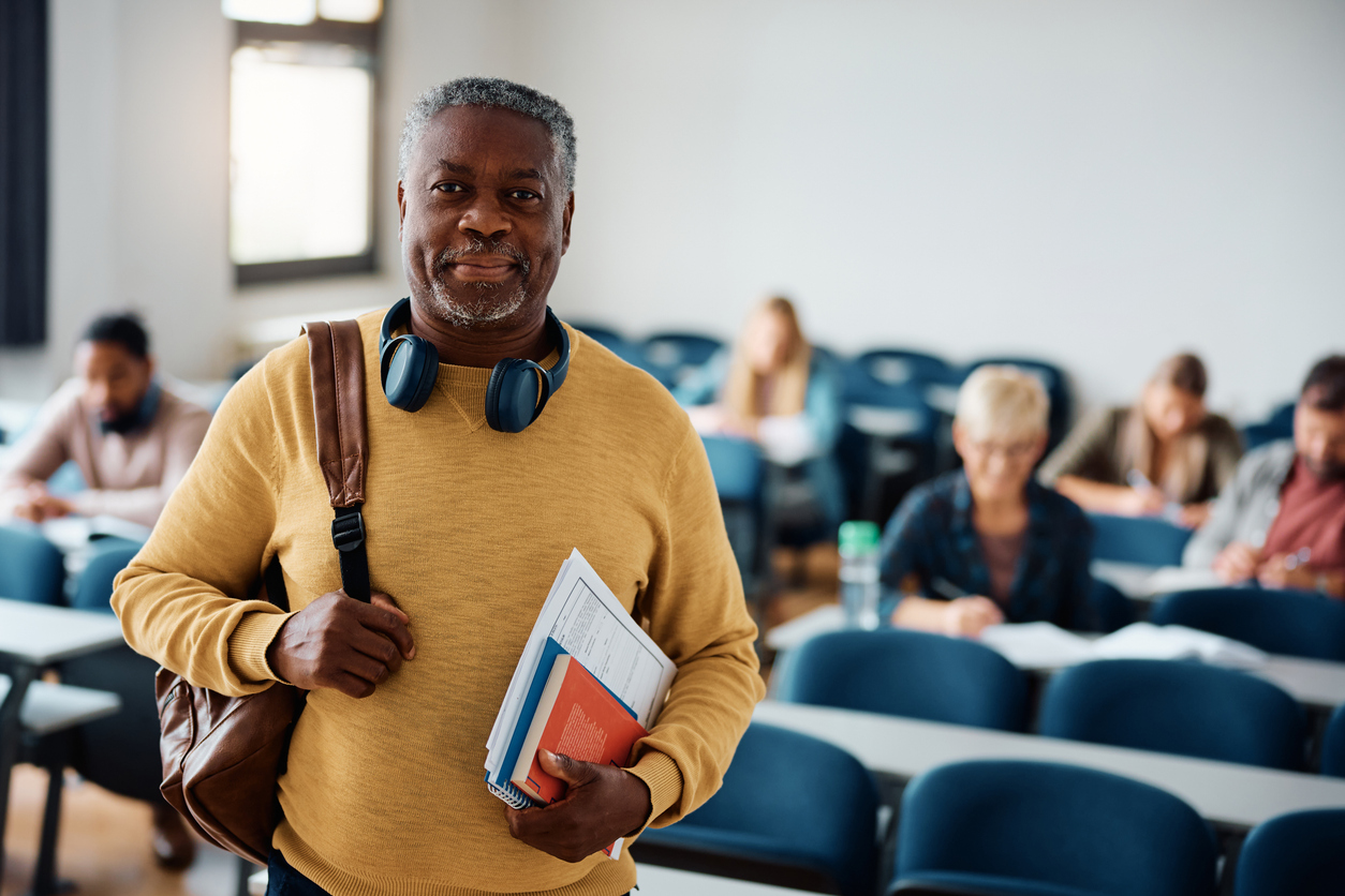 Smiling African American senior man attending a class in lecture hall and looking at camera.