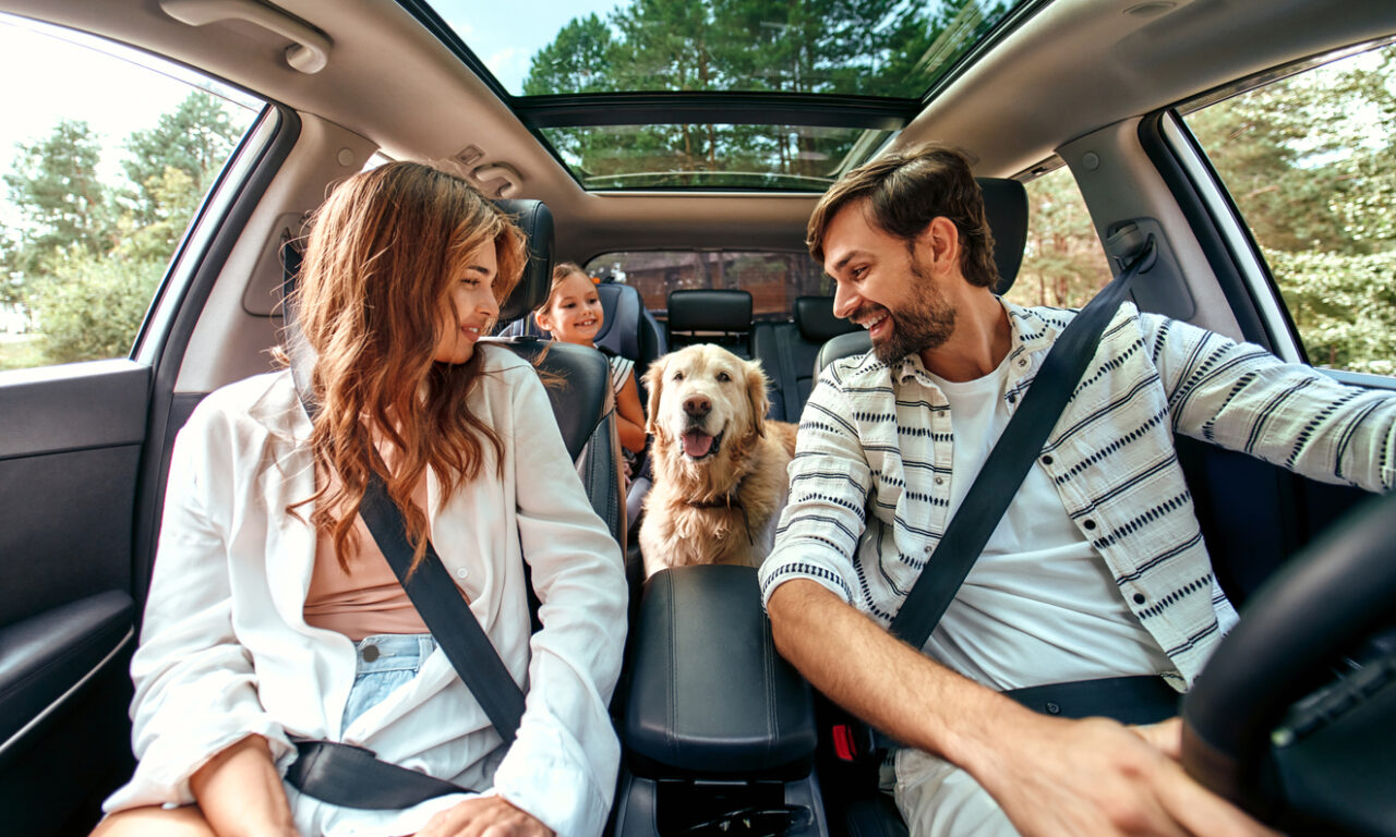 Excited family sitting in car with dog.
