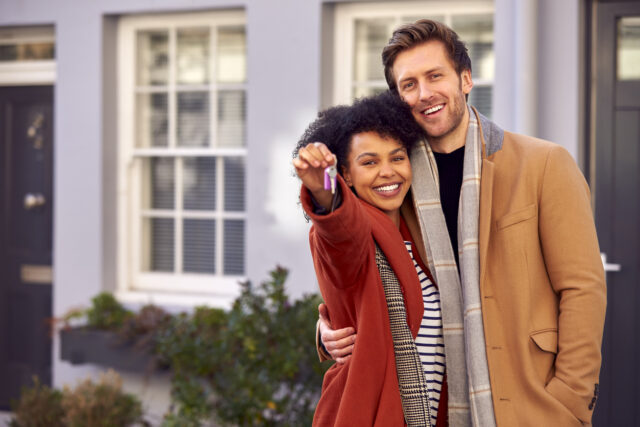 Portrait Of Multi Cultural Couple Outdoors On Moving Day Holding Keys To New Home