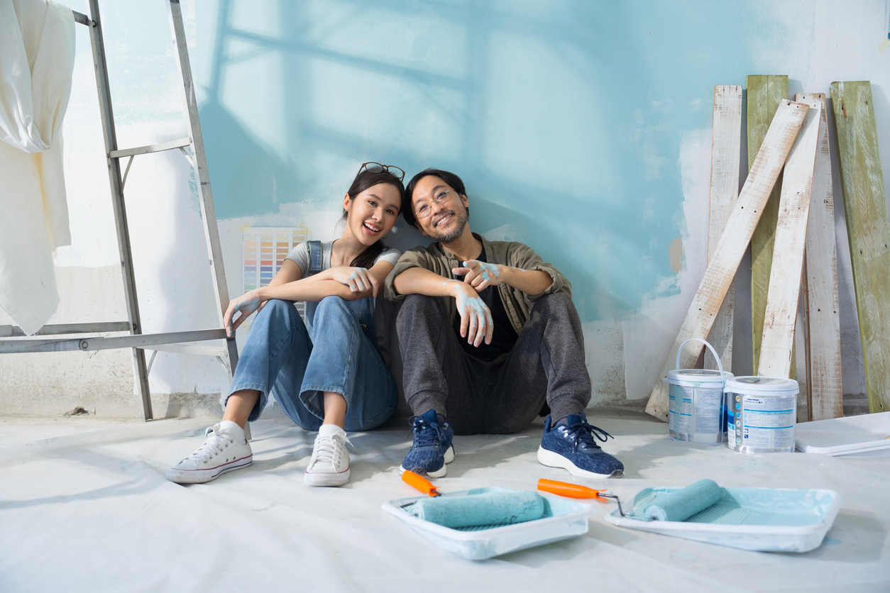 Young Asian couple renovates and paints room blue in new apartment.