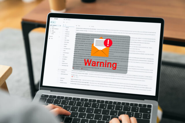 Person using laptop opening emails receives warning notification.