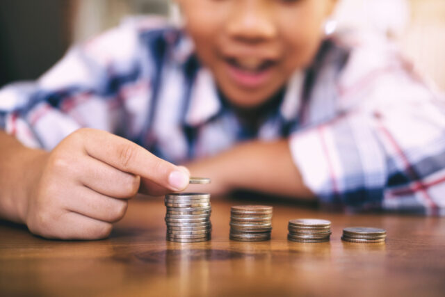 Child making a coin stack on table.