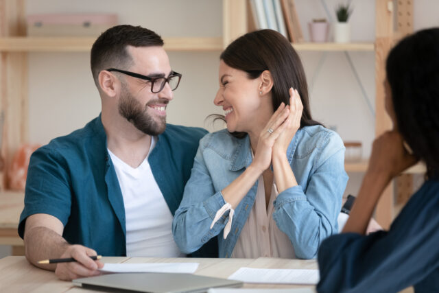 Excited young couple sign deal at office meeting.