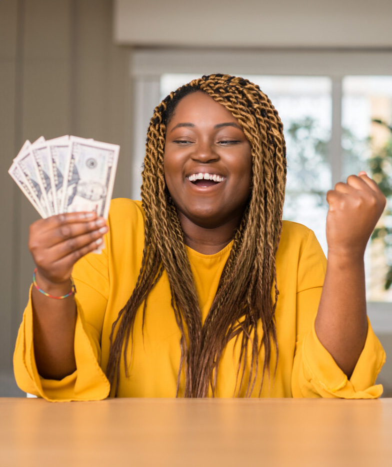 African American woman smiles joyfully at hand full of cash.